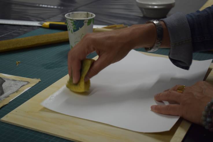 Eine Hand tupft ein Blatt Papier mit einem nassen Schwamm ab